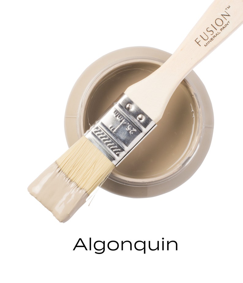 May include: A jar of Fusion Mineral Paint in the color Algonquin. The jar is open and a paintbrush is resting on the rim. The paintbrush is partially dipped in the paint.