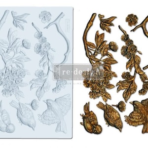 May include: A silicone mold for baking or crafting features a delicate floral design with birds. The mold is light blue and has a textured surface. The design includes branches, leaves, flowers, and birds.