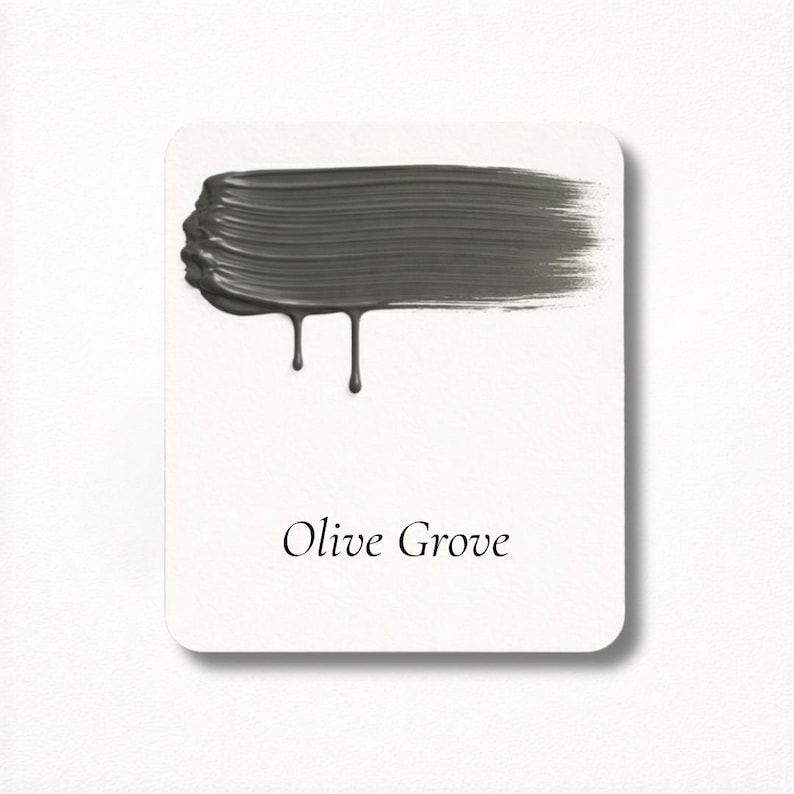 May include: A paint swatch card with a brushstroke of dark olive green paint. The paint has a textured appearance with drips. The words "Olive Grove" are printed in a serif font below the paint swatch.