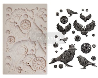 Puede incluir: Molde de silicona con un diseño de pájaros, engranajes y coronas. El molde es blanco y tiene una superficie texturizada. El diseño es de estilo steampunk.