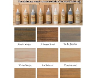 May include: A collection of eight bottles of wood stain labeled "Voodoo Gel Stain". The bottles are arranged in a row, and the stain colors are shown in the swatches below. The colors are: Black Magic, Tobacco Road, Up In Smoke, White Magic, Au Naturel, Fireside Ash, Bleached Cypress, Whiskey Barrel, and Charred Hickory.