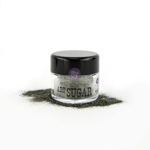 May include: A small jar of Art Sugar glitter with a black lid. The jar is clear, revealing gray glitter inside. The words "Art Sugar" are printed on the front of the jar, with a small amount of glitter spilled around it.