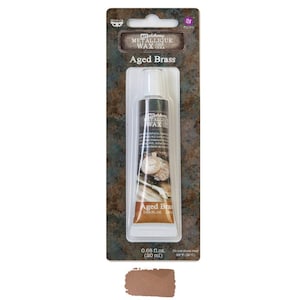 May include: A tube of metallic wax in aged brass color. The tube is labeled "Art Alchemy Metallic Wax Cera Aged Brass" and is 0.68 fl oz (20 ml).