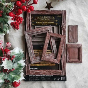 May include: A brown silicone decor mould for crafting vintage timber frames, measuring 5 inches by 8 inches. The mould features recessed designs for two rectangular frames and two solid rectangular panels with a wood grain texture.