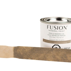 May include: A 237 ml can of Fusion Mineral Paint in the color Driftwood. The can is labeled with the product name, color name, and instructions for use. A wooden paint stick shows the color of the paint.