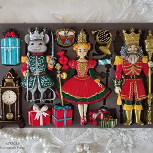 May include: A silicone mold for making a Nutcracker Party themed cake. The mold features a nutcracker, a ballerina, a mouse, a clock, a gift box, a drum, a candy cane, and a trumpet. The mold is made of food-grade silicone and is dishwasher safe.