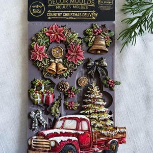May include: A grey silicone decor mould titled Country Christmas Delivery featuring raised designs of a red pickup truck carrying a Christmas tree, a poinsettia wreath, bells, gift boxes, a bow, pinecones, and holly berries for crafting projects.