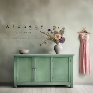 May include: A green painted cabinet with three doors and silver knobs. The cabinet is sitting on a light wood floor. The wall behind the cabinet is painted a light green color. The text "Alchemy by Fusion" and "A blend of limestone & chalk" is visible on the wall.
