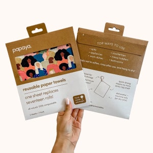 May include: Two brown paper packages with a reusable paper towel inside. The towel features a colorful pattern of women's faces. The packaging says "papaya. reusable paper towels" and "one sheet replaces seventeen rolls!"  The packaging also includes instructions on how to use the towels, including "quick-drying means no more stinky rag smell!" and "dishwasher machine safe (air dry only)".