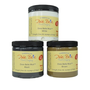 May include: Three jars of Dixie Belle Mud paint in white, black, and brown. The jars are labeled with the Dixie Belle Paint Company logo and the color of the paint. The text on the jars reads "Dixie Belle Mud" and "Straight from the swamps of Dixie".