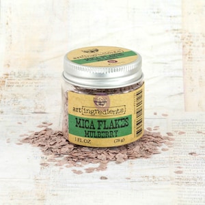 May include: A small glass jar with a silver lid filled with pink mica flakes. The jar has a brown label with the text "art ingredients Mica Flakes Mulberry 1 fl oz (28 g)".