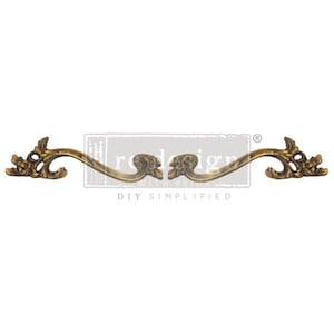 May include: A pair of ornate gold-toned metal drawer pulls with a decorative floral design. The pulls are curved and have a graceful, elegant style.