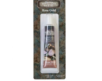 May include: A tube of rose gold metallic wax for crafting and decorating. The tube is labeled "alchemy METALLIQUE WAX CERA" and "Rose Gold". The tube is 0.68 fl. oz. (20 ml).