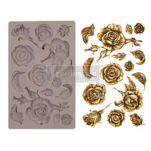 May include: A gray silicone mold and a sheet of gold-colored rose transfers. The mold features various rose designs, including open blooms, buds, and leaves. The transfers showcase detailed gold roses and foliage, ideal for crafting and decorative projects.