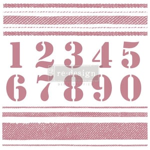 May include: A set of pink rubber stamps featuring the numbers 1 through 9 and 0. The stamps are arranged in two rows. The numbers are in a bold, sans-serif font. There are two pink patterned lines above and below the numbers.