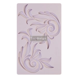 May include: A silicone mold for crafting with two ornate, swirling designs. The mold is white and features the text "re-design with prima DIY SIMPLICITIES".