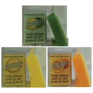 May include: Three packages of natural soap infused scrubbers. Each package has a different color scrubber: green, yellow, and orange. The packaging is white with the words "Natural Soap Infused Scrubber" and "SCRUBBY" in black text. The text "Easily removes paint, oil, dirt, grease & more!" is also printed on each package.