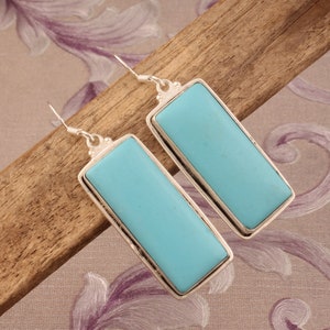 May include: A pair of silver dangle earrings with rectangular turquoise stones.