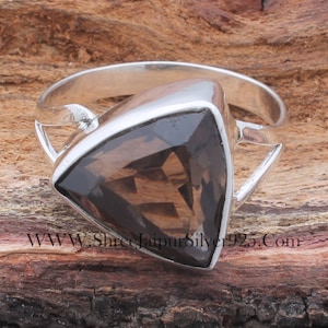 May include: A silver ring featuring a triangular, smoky quartz gemstone. The ring has a plain band and a bezel setting.