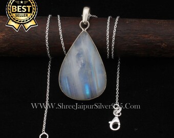 May include: A silver chain necklace with a teardrop-shaped pendant featuring a white moonstone. The pendant has a blue iridescent sheen. The necklace is on a wooden surface.  www.shreejaipursilver925.com