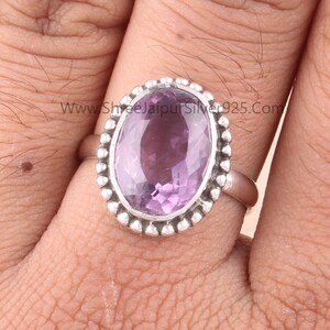 Pu&ograve; includere: Anello in argento con ametista ovale. L'ametista &egrave; di colore viola chiaro ed &egrave; circondata da un bordo argentato con perline. L'anello &egrave; su un dito.