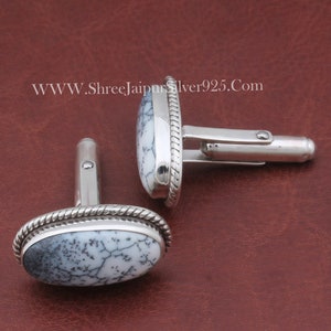 May include: A pair of silver cufflinks with a white and black dendritic agate stone set in each. The cufflinks have a rope-like border around the stone.