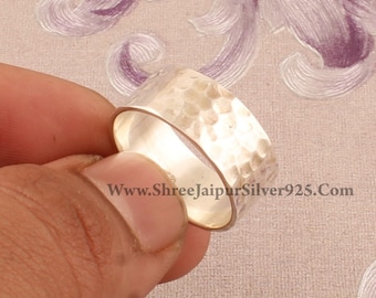 May include: A silver hammered band ring. The ring is wide and has a textured surface.