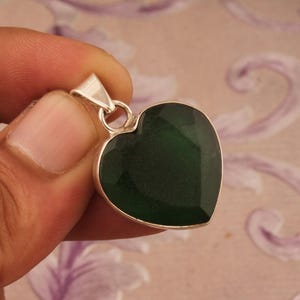 May include: A silver heart-shaped pendant with a dark green gemstone.