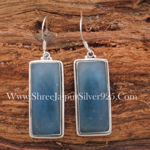 Puede incluir: Un par de pendientes de plata con colgantes rectangulares de piedra azul. Los pendientes tienen un diseño sencillo y son perfectos para el uso diario.