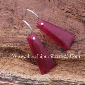 Puede incluir: Un par de pendientes de plata con un colgante de piedra roja. Los pendientes tienen un diseño sencillo y son perfectos para el uso diario.