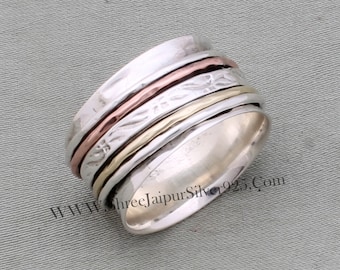 May include: A silver spinning ring with three bands of copper, gold, and silver. The ring has a textured surface and a floral design.