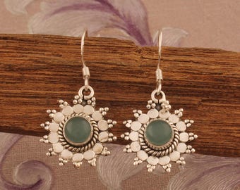 May include: Silver earrings with a blue-green gemstone set in a starburst design.