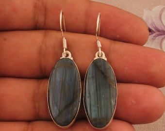 May include: A pair of silver dangle earrings with oval-shaped labradorite gemstones. The gemstones have a dark blue and green iridescent sheen.