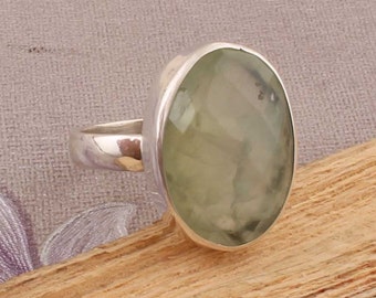 May include: A silver ring with a large, oval-shaped, light green gemstone.
