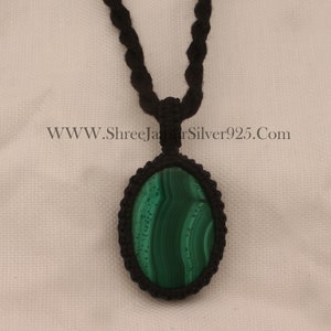 Peut inclure: Un pendentif en malachite verte sur un collier en cordon noir. Le pendentif est de forme ovale et a un cordon tressé.