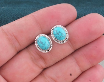 Puede incluir: Un par de pendientes de botón ovalados con piedras de color turquesa brillante y vetas de color gris oscuro. Cada piedra está engastada en un marco de plata pulida con un detalle de borde de cuerda trenzada alrededor del óvalo.