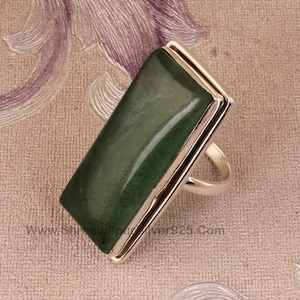 May include: A silver ring with a large, rectangular, green gemstone. The ring has a double band design.