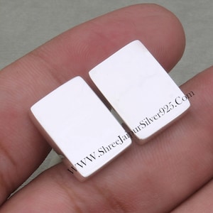 Puede incluir: Dos gemelos rectangulares de plata. Los gemelos son lisos y brillantes. El texto "WWW.ShreeJaipurSilver925.Com" es visible en los gemelos.