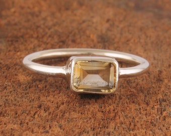 May include: A silver ring with a rectangular, light brown gemstone.
