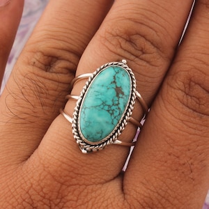 May include: A silver ring with a turquoise oval stone set in a twisted silver band.