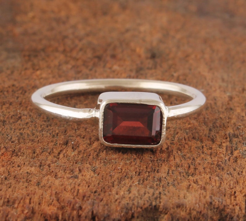 May include: A silver ring with a rectangular red gemstone.