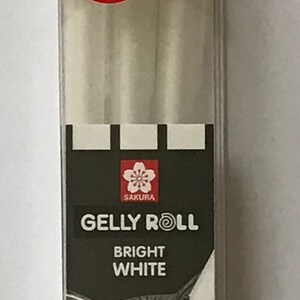 May include: A pack of three Sakura Gelly Roll pens in bright white. The pens are in a clear plastic package with a red "NEW!" sticker. The package shows a black and white illustration of a fox's face. The pens have three different tip sizes: 0.3 mm, 0.4 mm, and 0.5 mm, labeled as fine, medium, and bold.