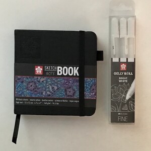 Square hardback sketchbook with black pages and  x3 Fine white Gelly roll pens