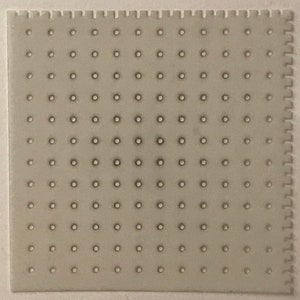 May include: A white, rectangular, plastic sheet with a grid of evenly spaced, small, round holes.