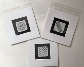 May include: Three black and white framed drawings of geometric patterns. The drawings are in white matted frames with a white background.