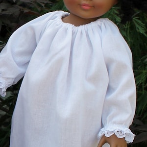 May include: A white doll with black hair wearing a white dress with lace trim. The dress has a gathered neckline and long sleeves.