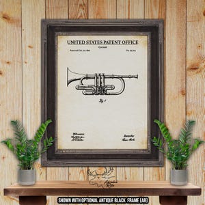 Op de afbeelding: Ingelijste vintage patentafdruk van een cornet, met een gedetailleerde zwart-wit illustratie. De afdruk, van het United States Patent Office, is geplaatst tegen een crèmekleurige achtergrond en ingelijst in een donker, antiek ogend frame. De tekst "Cornet" en patentinformatie zijn zichtbaar.
