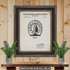 May include: Framed vintage kitchen timer patent print. The black and white diagram, from the United States Patent Office, shows a timer design. The print is in a dark gray frame, and the text reads "Kitchen Timer" and "Patented May 13, 1952."