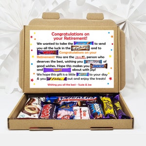 May include: A brown cardboard box with a colourful card on top that says "Congratulations on your Retirement!" The card has a variety of chocolate bar wrappers on it, including Galaxy, Wispa, Twirl, and Flake. The box is open and filled with a variety of chocolate bars.