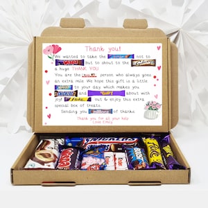 May include: A brown cardboard box with a thank you note inside. The note is decorated with chocolate bar wrappers and says "Thank you! We wanted to take the Wispa but to shout to the Galaxy a huge THANK YOU. You are the person who always goes an extra mile. We hope this gift is a little BOOST to your day which makes you SNICKERS and Twirl about with joy! Flake. out & enjoy this extra special box of treats. Sending you of thanks. Thank you for all your help Love Emily". The box is open and filled with various chocolate bars.